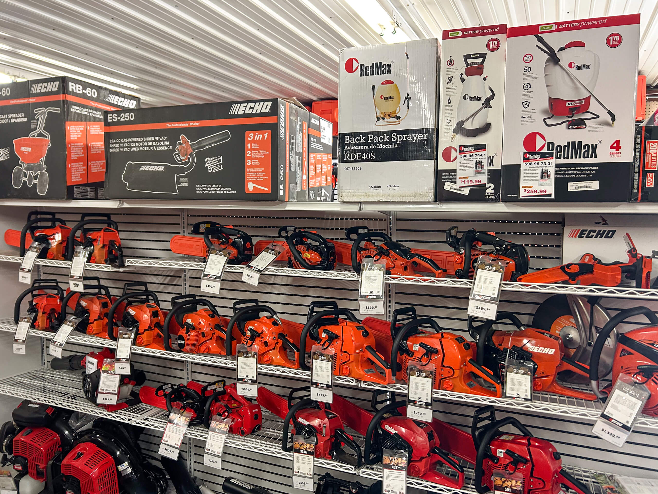 11.4.25 AK Small Engines Gallery 2-9 a shelf of orange echo chain saws