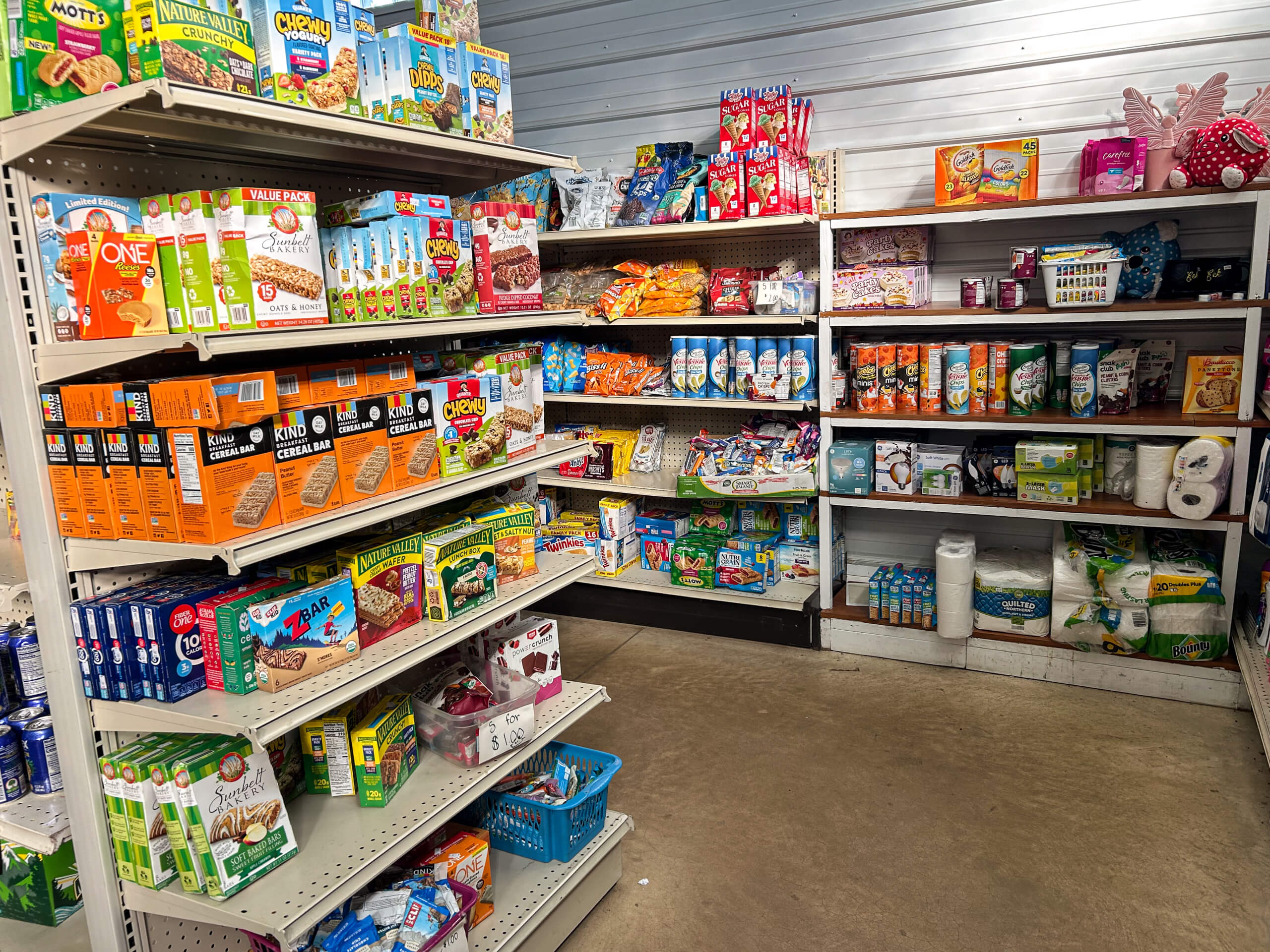 Sunrise Discount Grocery Store Colon MI Shelves in a store stocked with assorted snacks, cereal boxes, household supplies, cleaning products, toilet paper, and baby items.