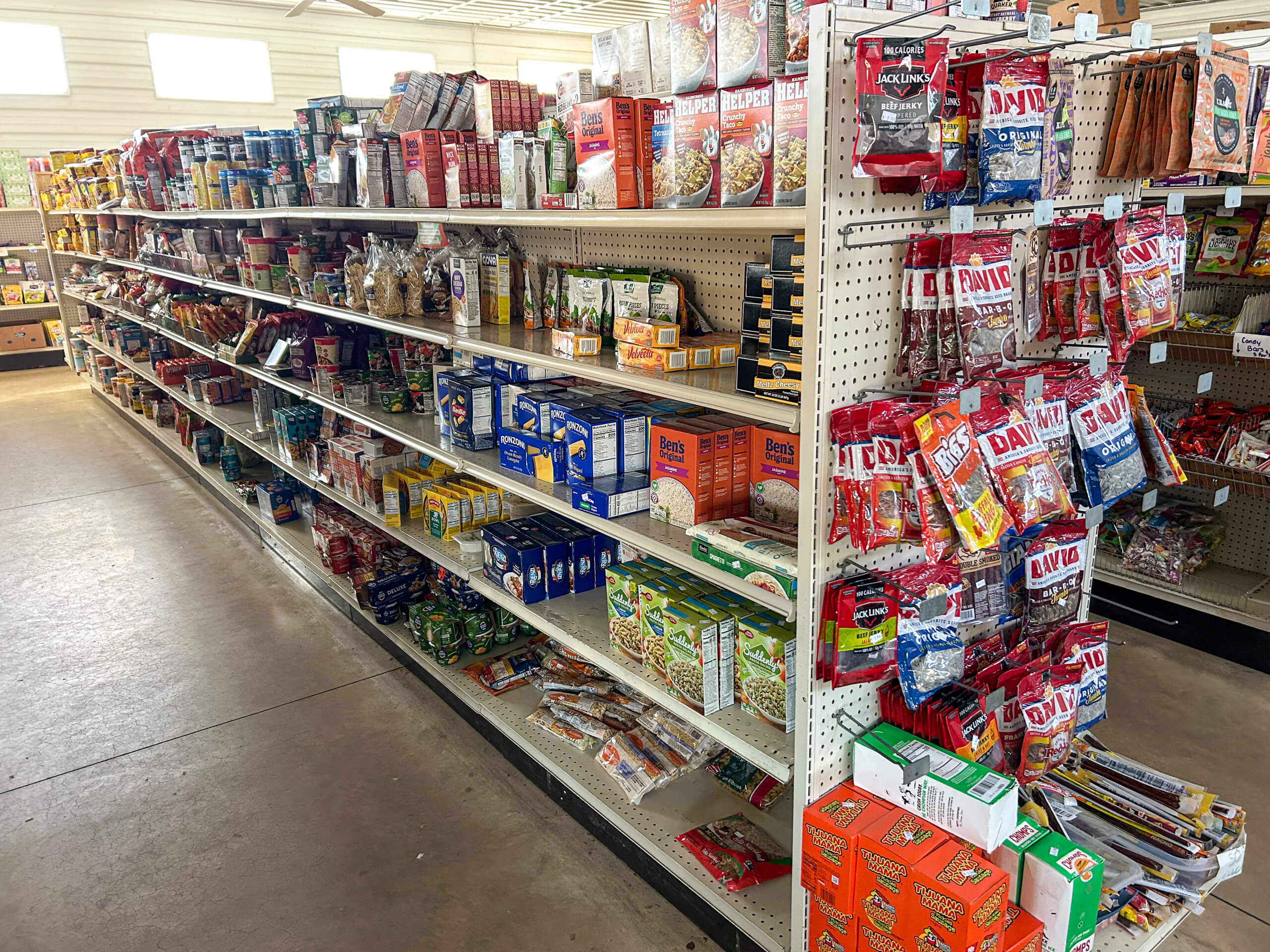 Sunrise Discount Grocery Store Colon MI A grocery store aisle with shelves stocked with various snacks, packaged foods, and bags of sunflower seeds on display.