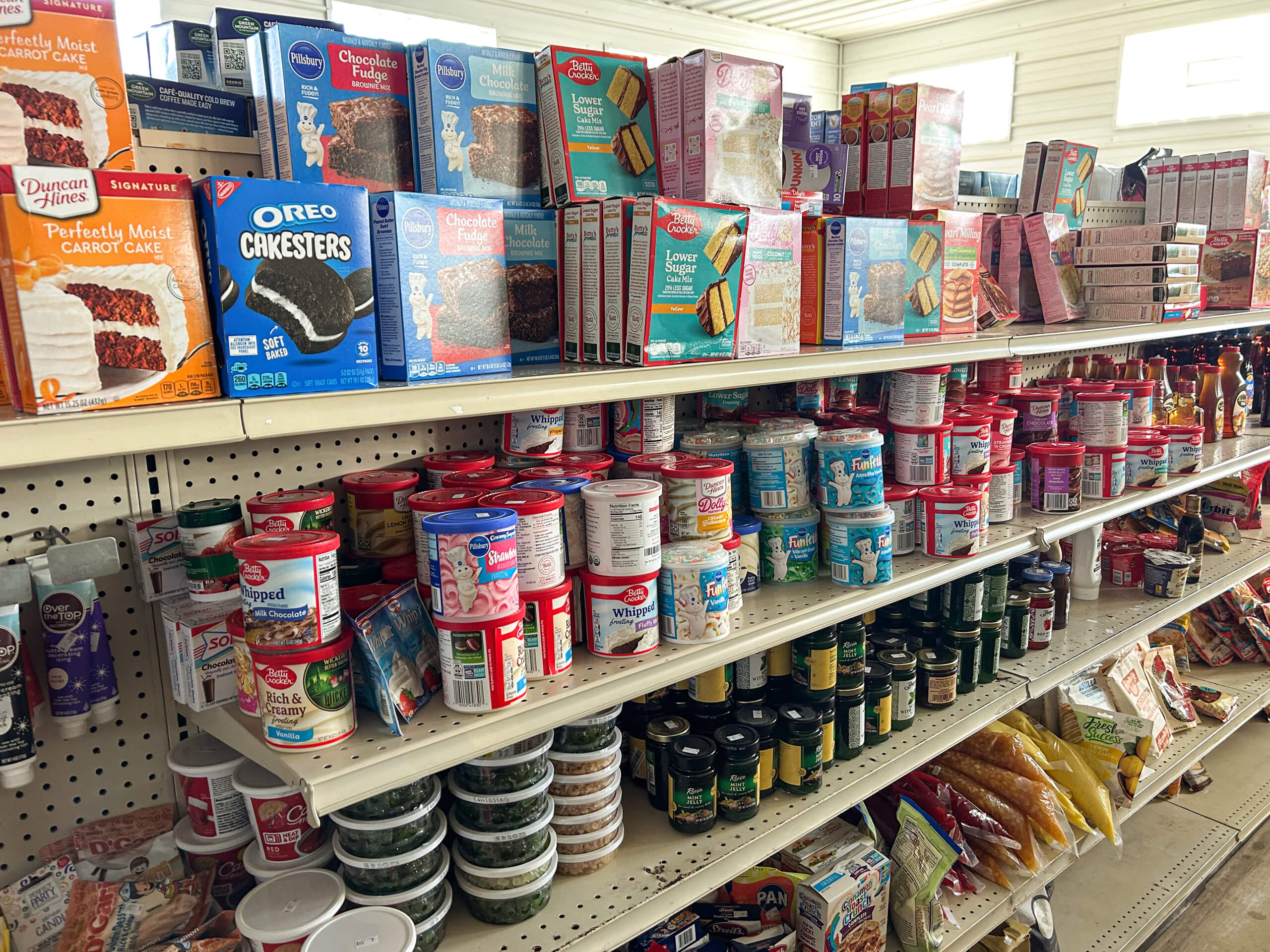 Sunrise Discount Grocery Store Colon MI Shelves stocked with cake mixes, frosting containers, cookies, canned goods, and assorted baking and pantry items in a grocery store aisle.