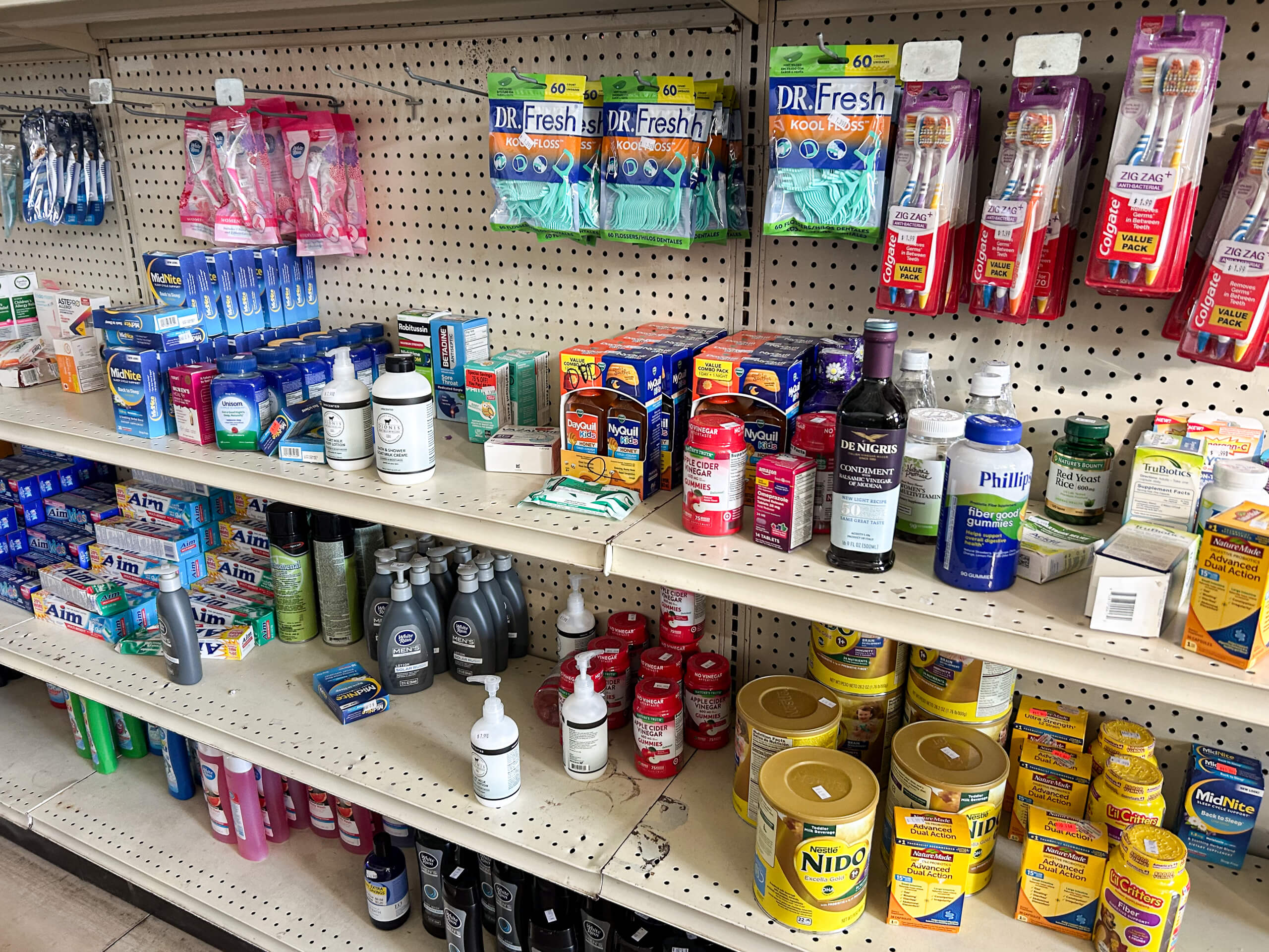 Sunrise Discount Grocery Store Colon MI Shelves stocked with dental care items, medications, mouthwash, baby formula, and personal hygiene products in a store.