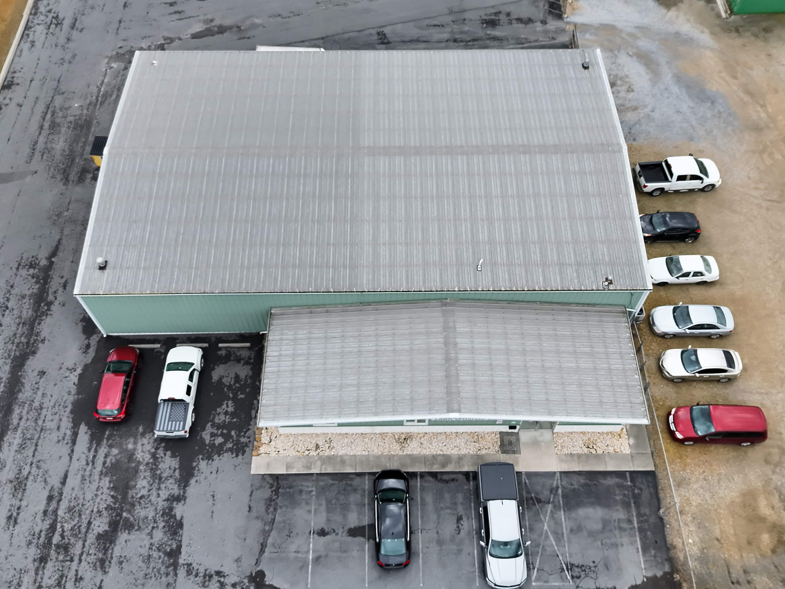 Winding Road Roofing After Restoration Hagerstown MD view of a building with a metal roof, adjacent parking lot, and several parked cars along the front and side.