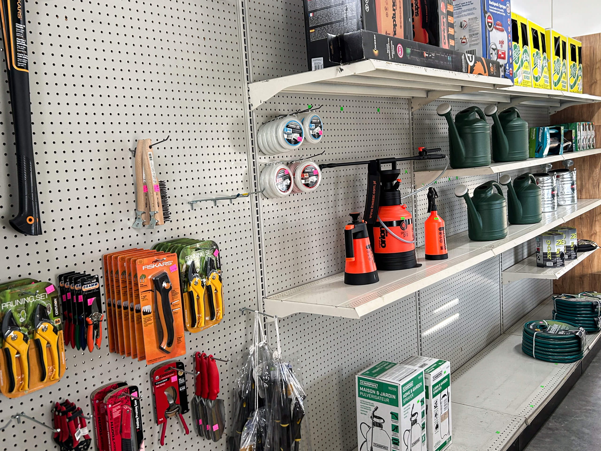 Graber Farm & Home Center Odon Indiana A store display with gardening tools, hose nozzles, watering cans, hoses, and plant sprayers arranged on pegboard shelves.