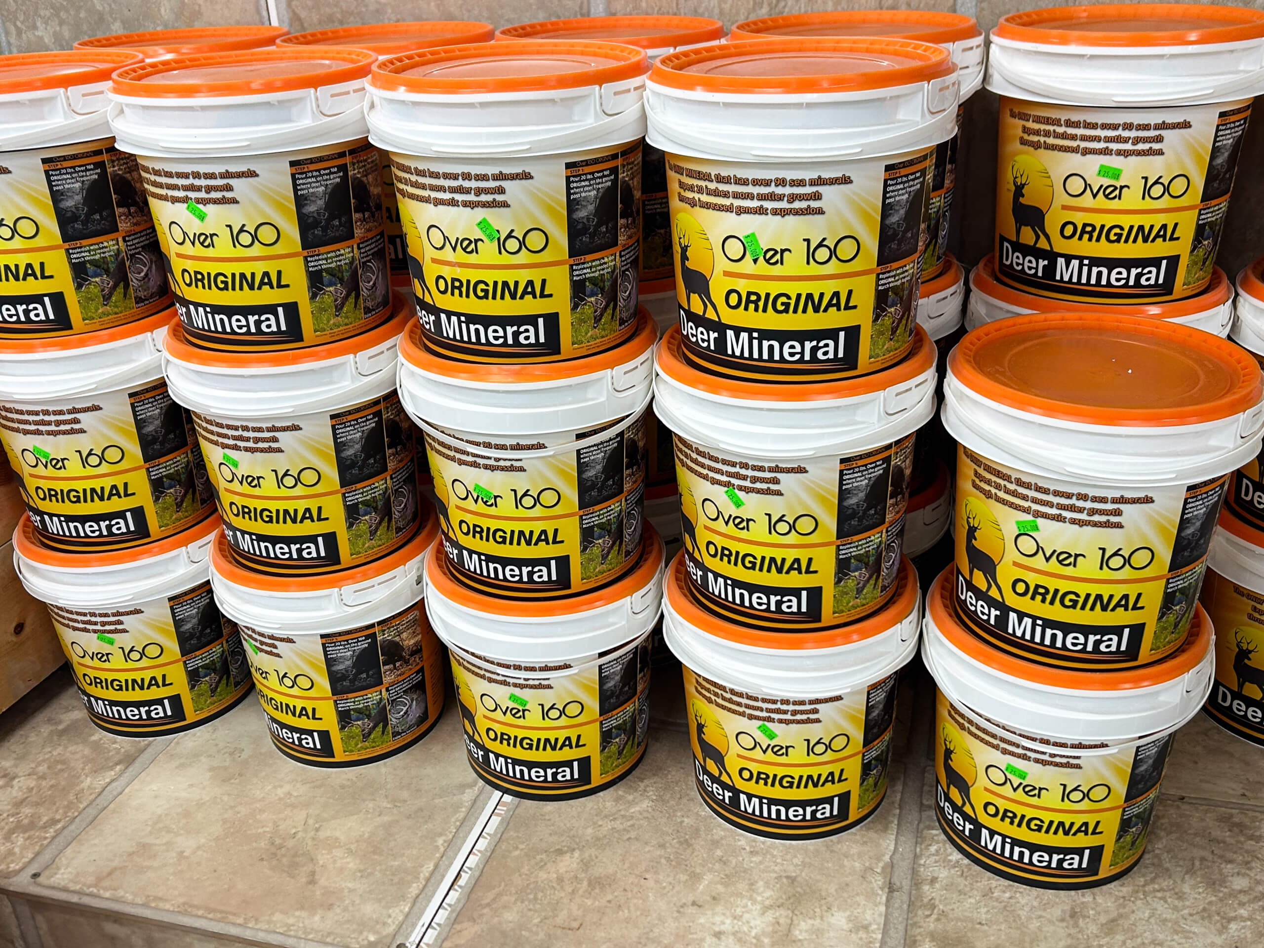 Graber Farm & Home Center Odon Indiana Stacks of white and orange buckets labeled "Over 160 Original Deer Mineral" are displayed on a tile floor in a store setting.