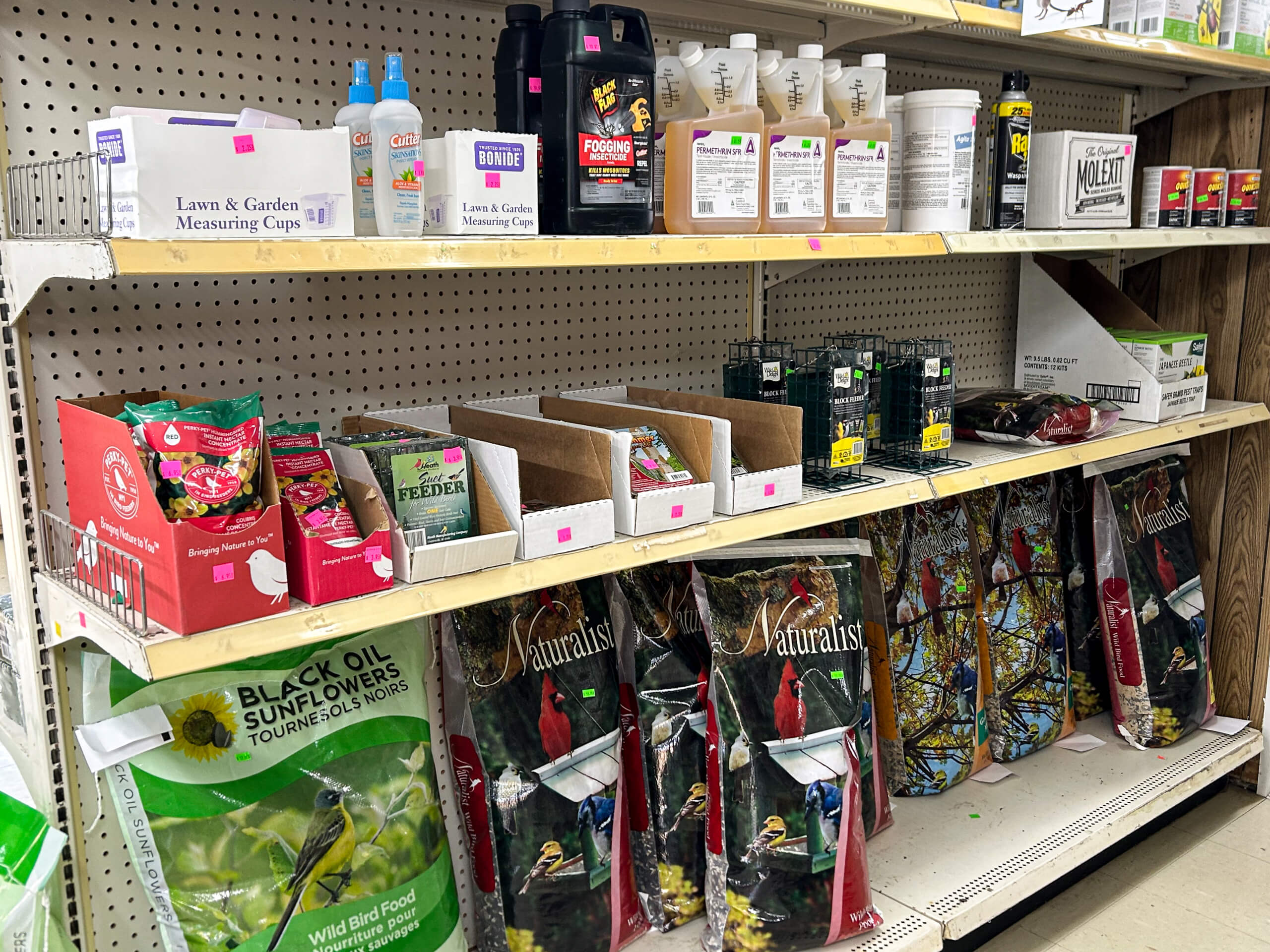 Graber Farm & Home Center Odon Indiana Store shelves with various gardening supplies, including bird seed bags, liquid fertilizers, plant food, and seed packets arranged on three levels.