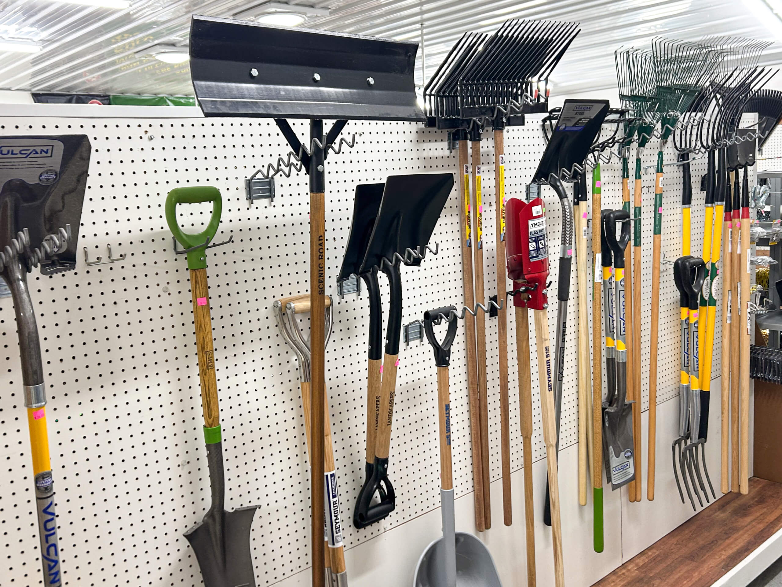 Graber Farm & Home Center Odon Indiana Various garden tools including shovels, rakes, and spades are displayed upright on a pegboard wall in a store.