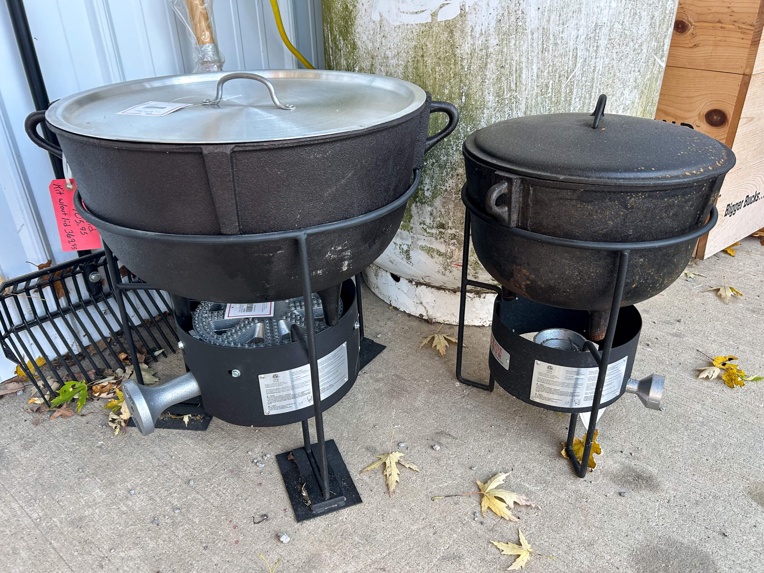 Country Side Harness Centerville MI Two large cast iron pots with lids are placed on outdoor gas burners, set on a concrete surface with scattered leaves around them.