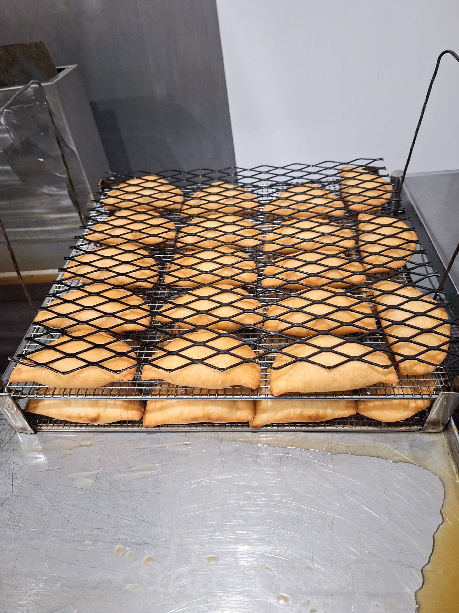 Dutch Heritage Bakery Sturgis MI A batch of golden-brown, rectangular pastries cooling on a metal rack above a stainless steel counter.