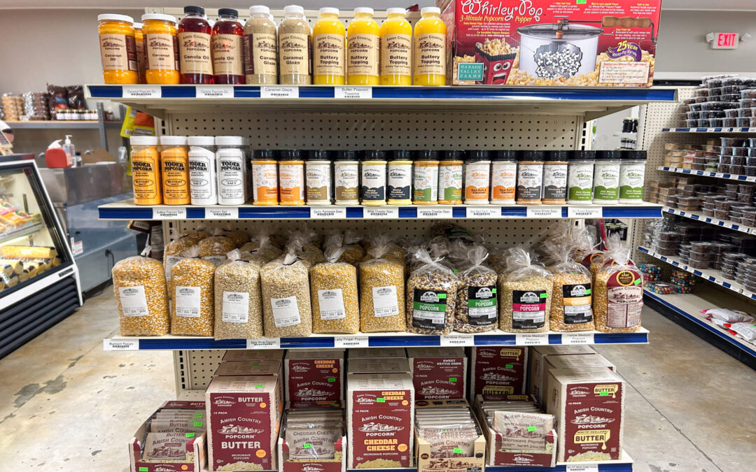 Millcreek Market Junction City Ohio Shelves display popcorn supplies including kernels, flavored toppings, seasoning shakers, popcorn oil bottles, and a Whirley Pop popcorn maker in a grocery store aisle.