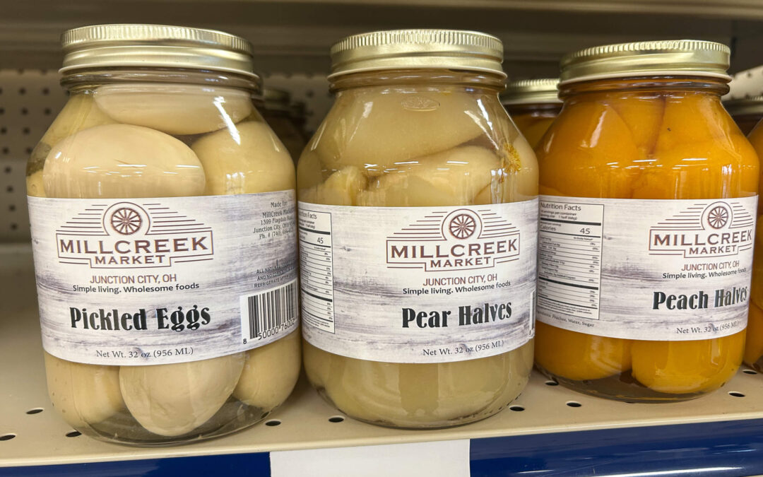 Millcreek Market Junction City Ohio Three jars of Millcreek Market preserves on a shelf: pickled eggs, pear halves, and peach halves.