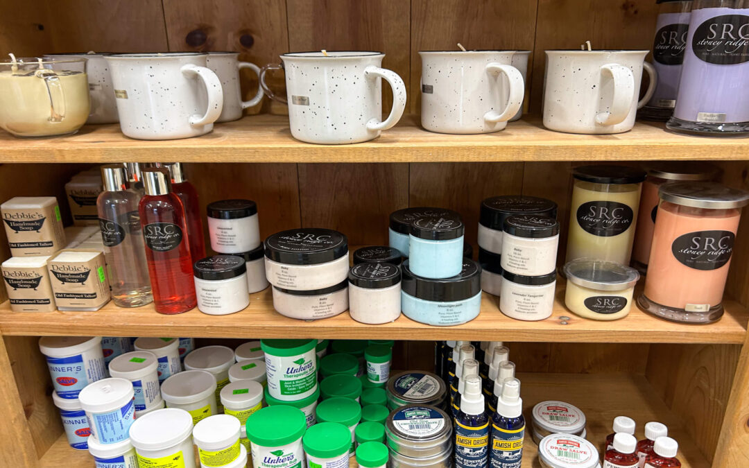 Millcreek Market Junction City Ohio Shelves stocked with various self-care products, including candles in mugs, jars of creams, spray bottles, tubs, and health ointments, against a wooden background.