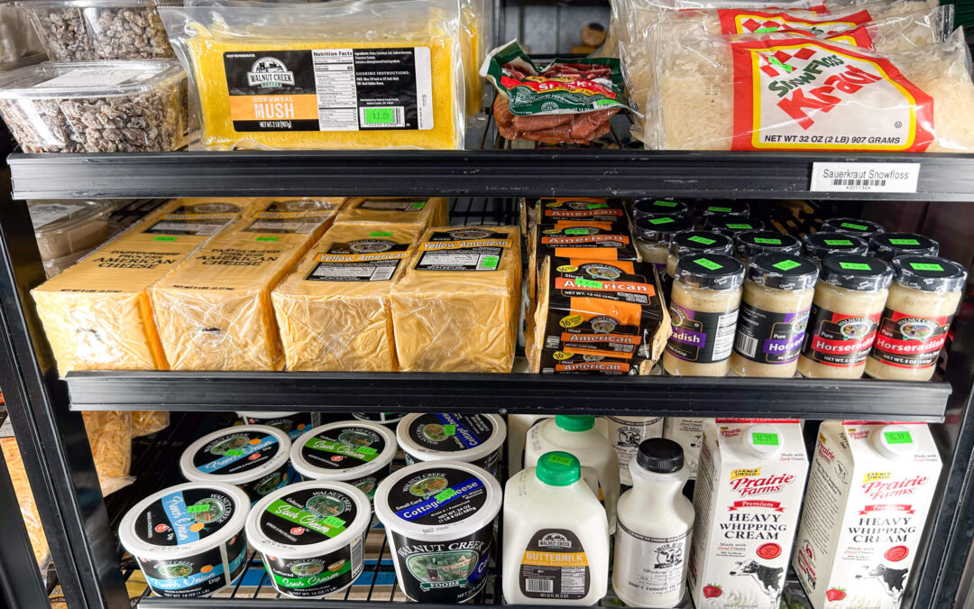 Millcreek Market Junction City Ohio Refrigerated grocery shelves stocked with cheese, hush relish, milk, cream, horseradish, sauerkraut, and bags of sauerkraut noodles.