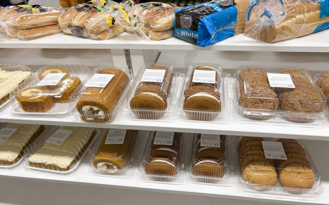 Millcreek Market Junction City Ohio Shelves display packaged baked goods including loaves of bread, hot dog buns, cakes, Swiss rolls, and cookies in a grocery store.