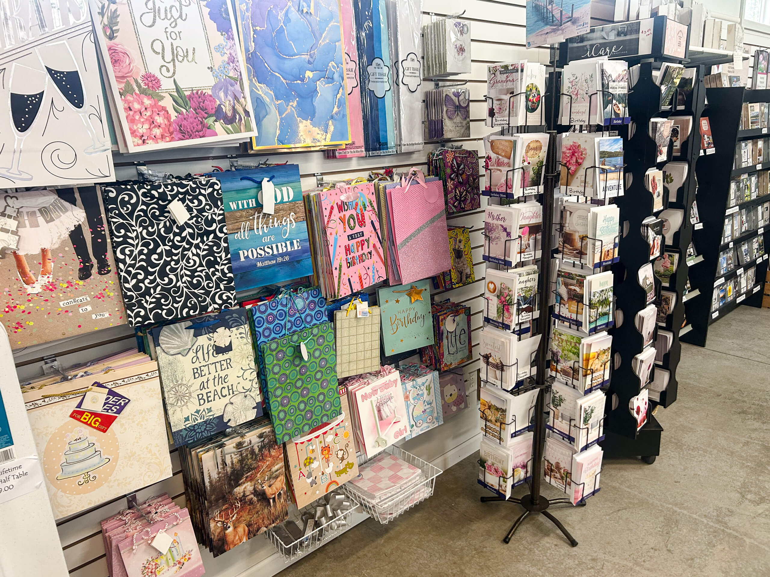 Miller's Variety Store Etna Green, IN Display of greeting cards, decorative gift bags, and art prints arranged on shelves and a rotating card stand inside a retail store.