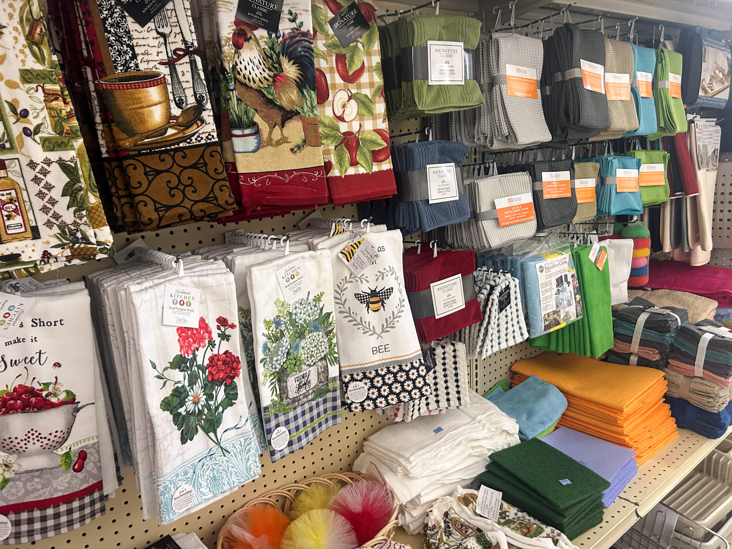 Miller's Variety Store Etna Green, IN A store display with various kitchen towels, dishcloths, and potholders in different colors and patterns arranged on shelves and hooks.