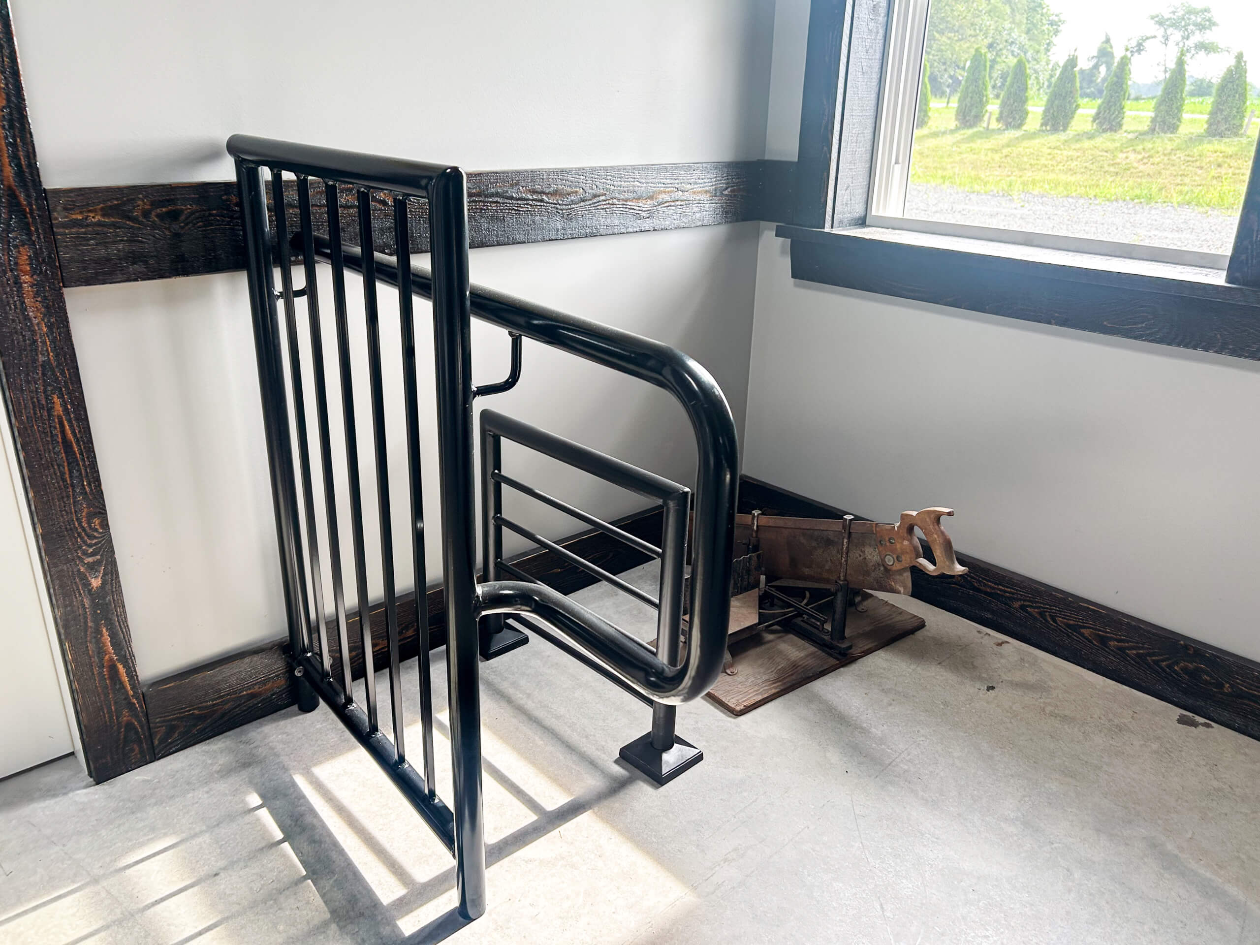 Zook's Metal Fabricating & Railings Allenwood, PA A black metal livestock gate and a small artificial calf dummy are positioned inside a barn near a window.