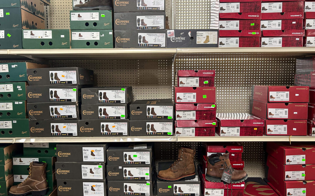 Shetler's Supplies Hardware Variety Bulk Foods Greenville PA Shelves stocked with various brands and sizes of boxed boots and shoes, with several pairs on display outside their boxes.