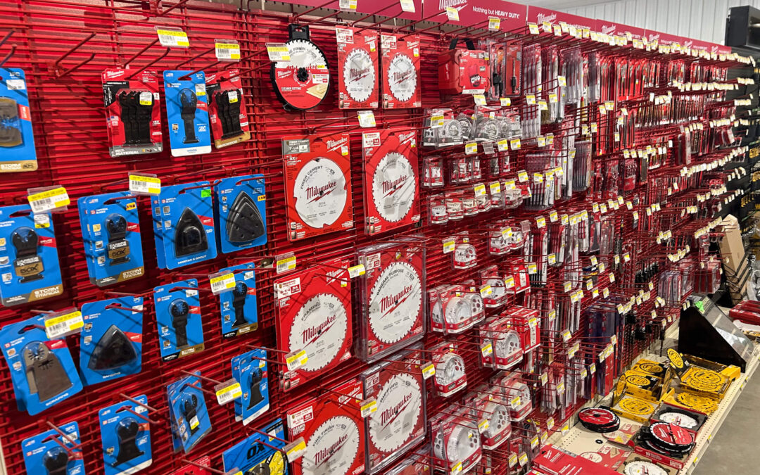 Shetler's Supplies Hardware Variety Bulk Foods Greenville PA Display wall with various Milwaukee brand power tool accessories, including saw blades, drill bits, and attachments, organized in packaging on red racks in a hardware store.
