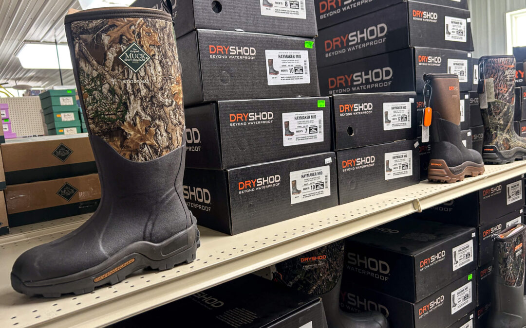 Shetler's Supplies Hardware Variety Bulk Foods Greenville PA Shelves display Dryshod brand waterproof boots in boxes, with a camouflage-pattern boot placed on the shelf for viewing in a retail store.