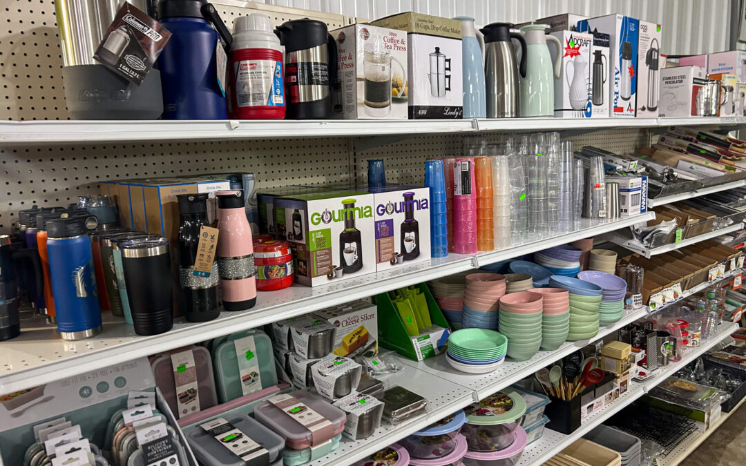 Shetler's Supplies Hardware Variety Bulk Foods Greenville PA Shelves in a store display various kitchenware items, including tumblers, bottles, dishes, cups, and storage containers, all organized and labeled with prices.