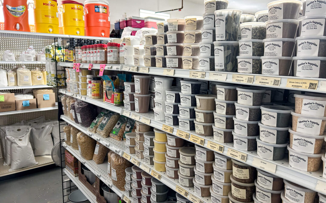 Shetler's Supplies Hardware Variety Bulk Foods Greenville PA Shelves in a store stocked with various plastic containers of powders and grains, including bulk food ingredients and supplements, with labels facing forward.