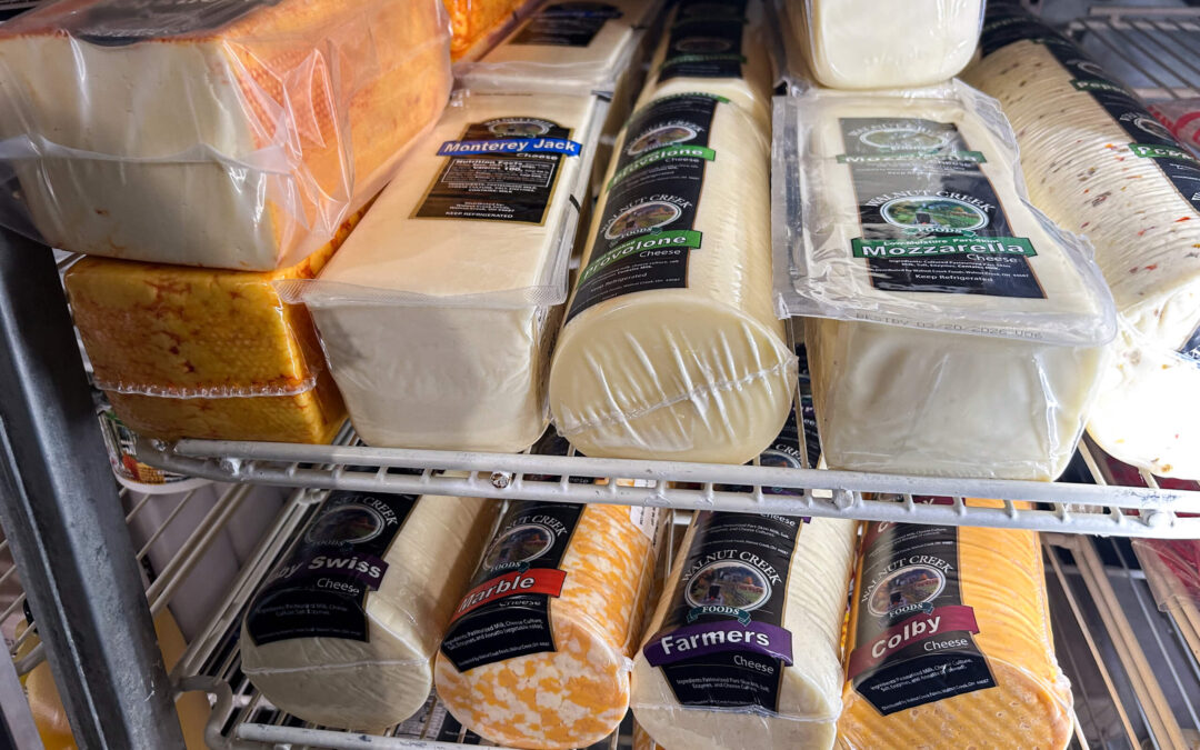 Shetler's Supplies Hardware Variety Bulk Foods Greenville PA Several types of packaged cheese, including Swiss, Colby, Mozzarella, and Monterey Jack, are displayed on metal refrigerator shelves.