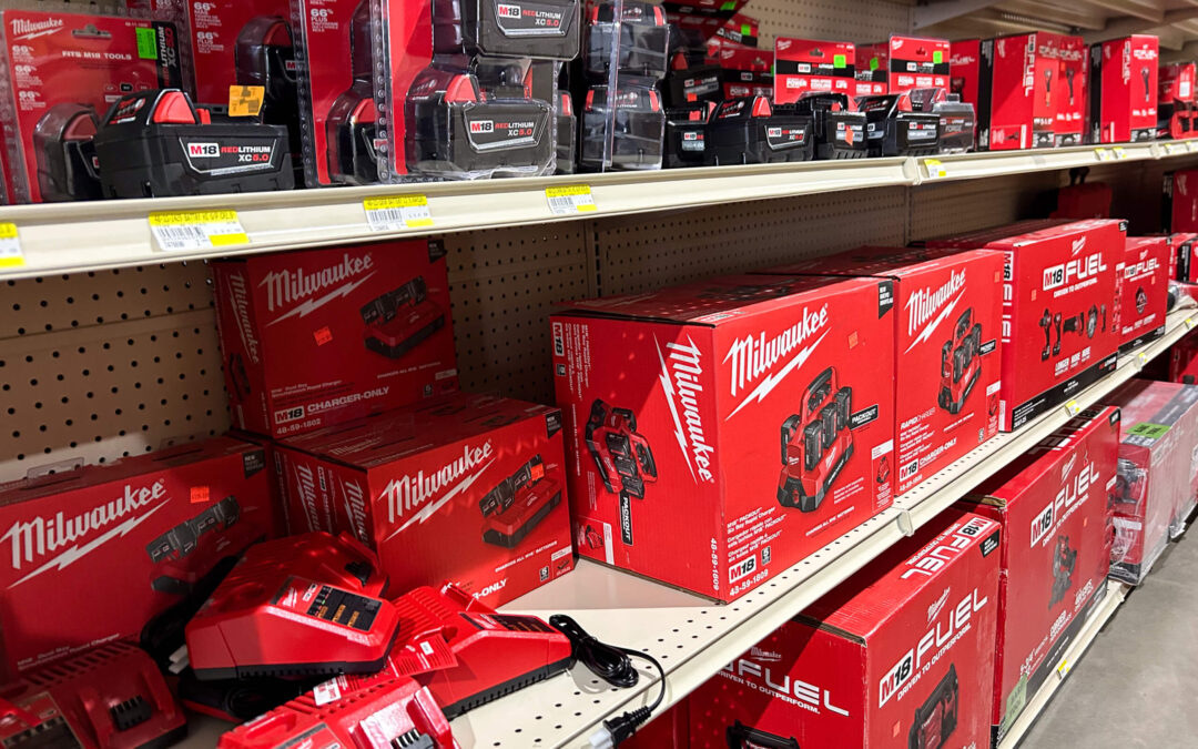 Shetler's Supplies Hardware Variety Bulk Foods Greenville PA Shelves stocked with Milwaukee power tool batteries, chargers, and accessories in red packaging at a hardware store.