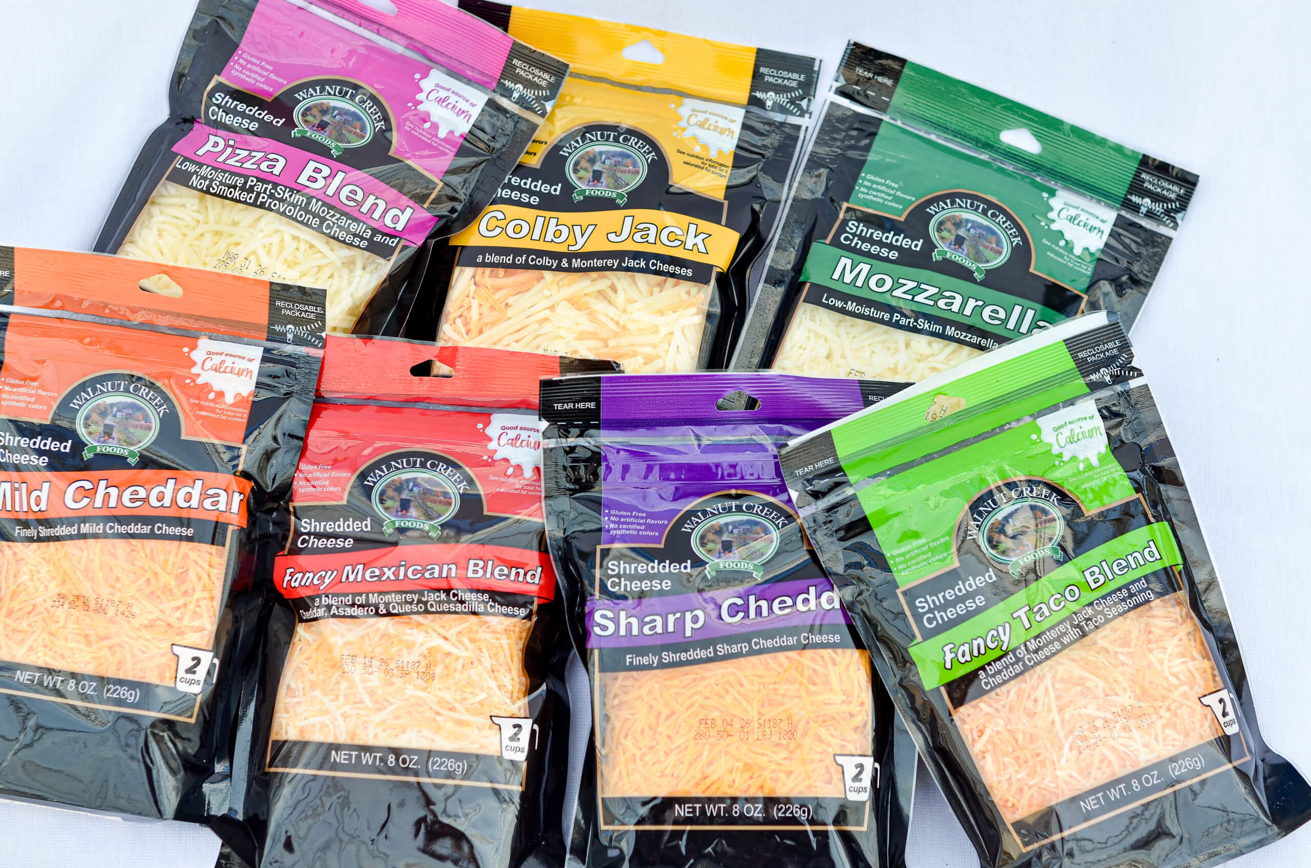 Nolt's Country Market Eldon, Missouri Eight assorted bags of shredded cheese in various blends and flavors, including Pizza Blend, Colby Jack, Mozzarella, Mild Cheddar, Fancy Mexican Blend, Sharp Cheddar, and Fancy Taco Blend.