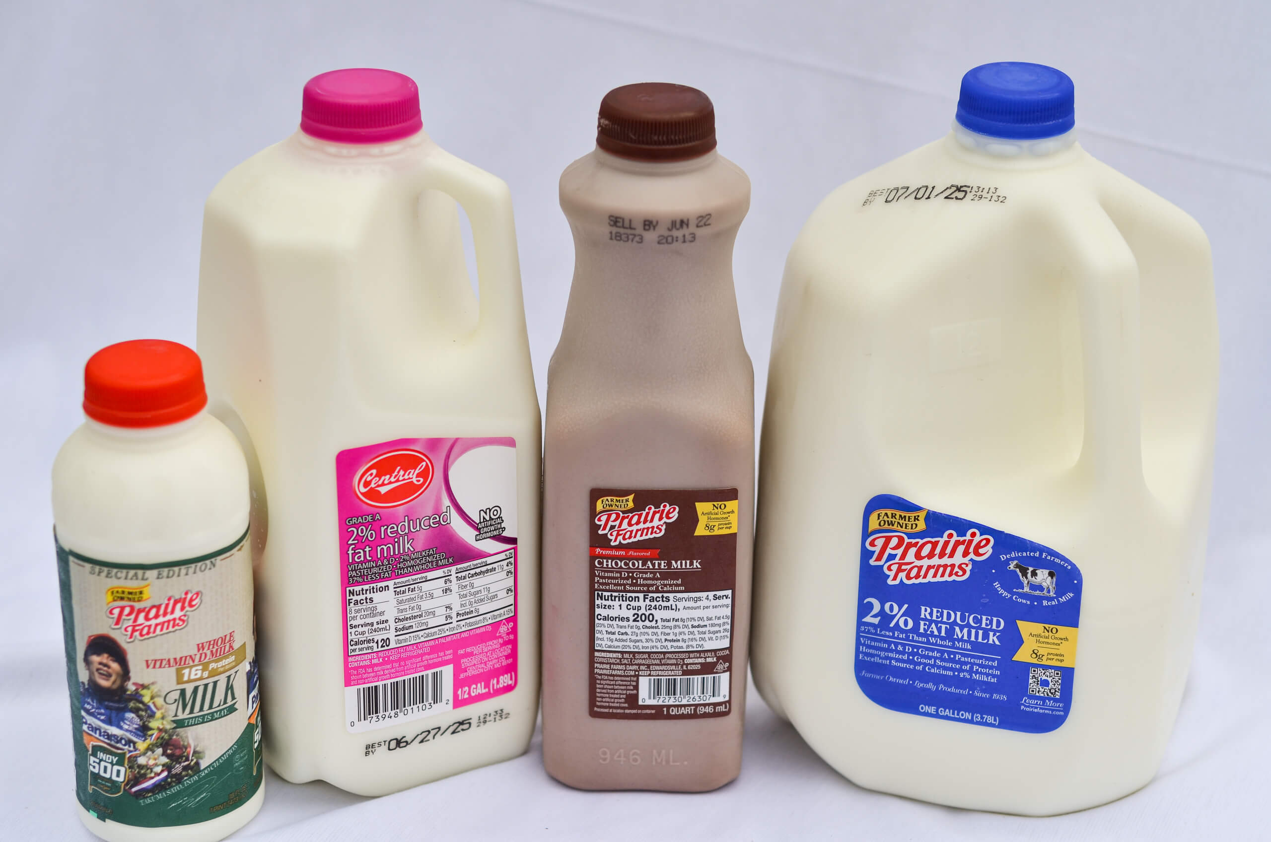 1.28.26 Nolt_s Country Market Cooler & Freezer Gallery 8 Four milk containers, including Prairie Farms and Central Dairy brands, with various types: whole, 2% reduced fat, and chocolate milk, displayed on a white background.