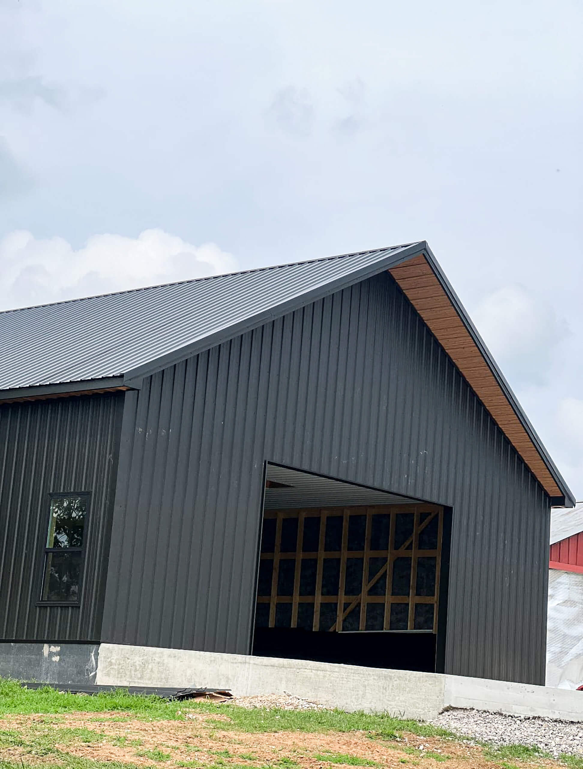 Bud's Construction Miunfordville KY A black metal building with an unfinished large open entry, set on a concrete foundation with visible wood framing inside.