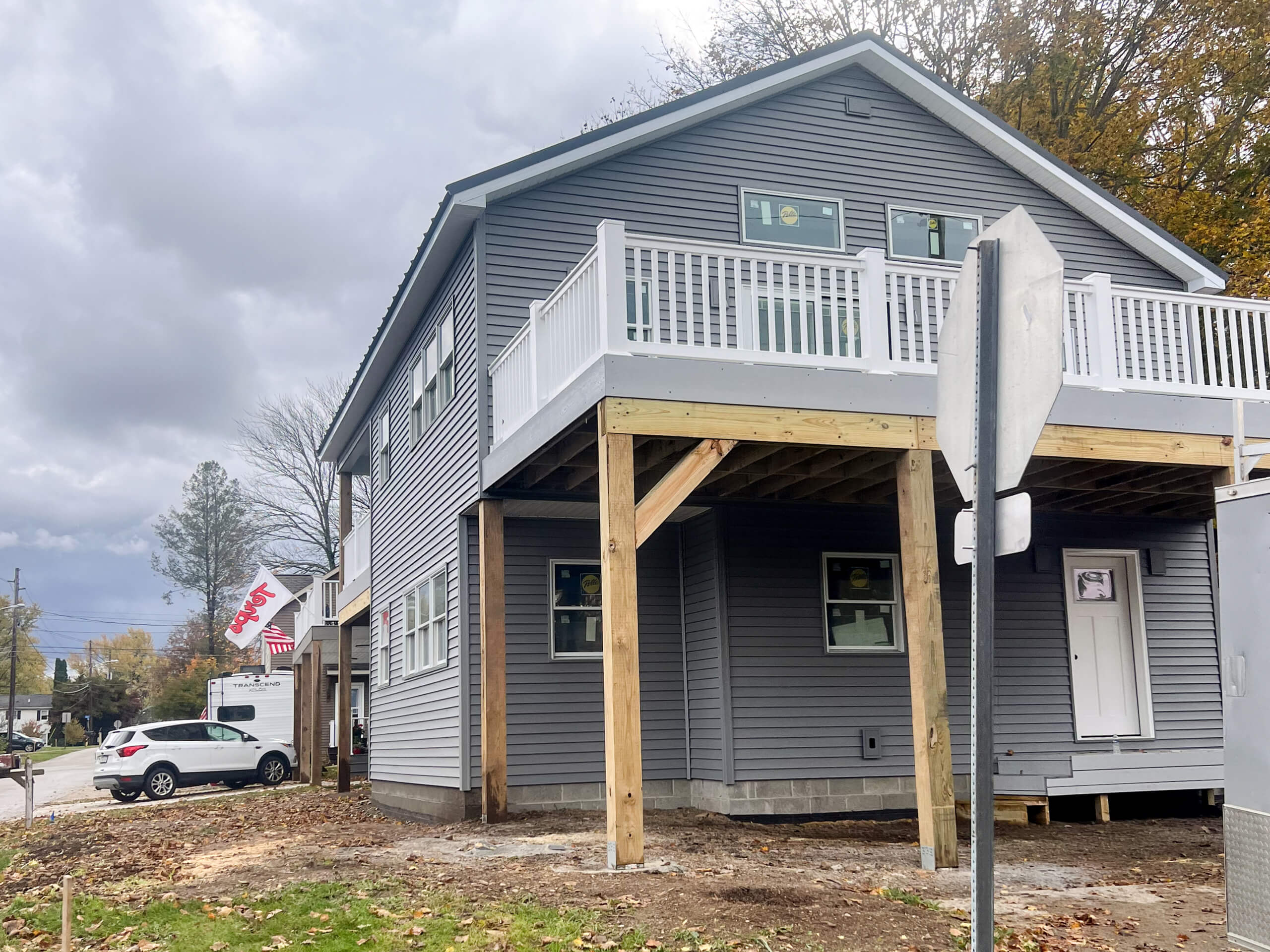 Crawford County Roofing Spartansburg PA Two-story gray house with a raised porch under construction, wooden support beams, and a "SOLD" sign on a van parked nearby.