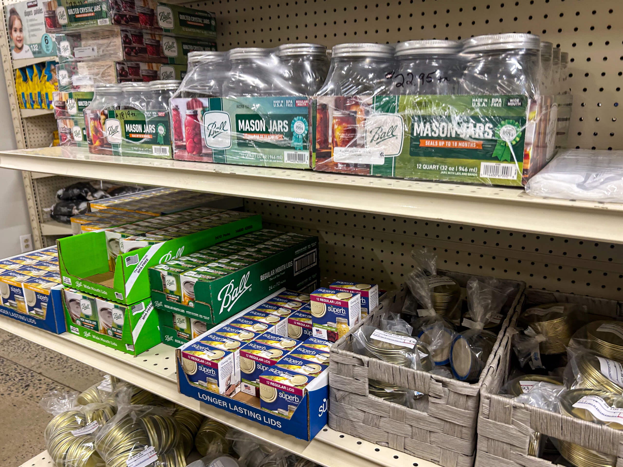 Jamar Groceries Kutztown PA Shelves display glass mason jars, boxes of jar lids, and baskets of metal jar lids in a store aisle.