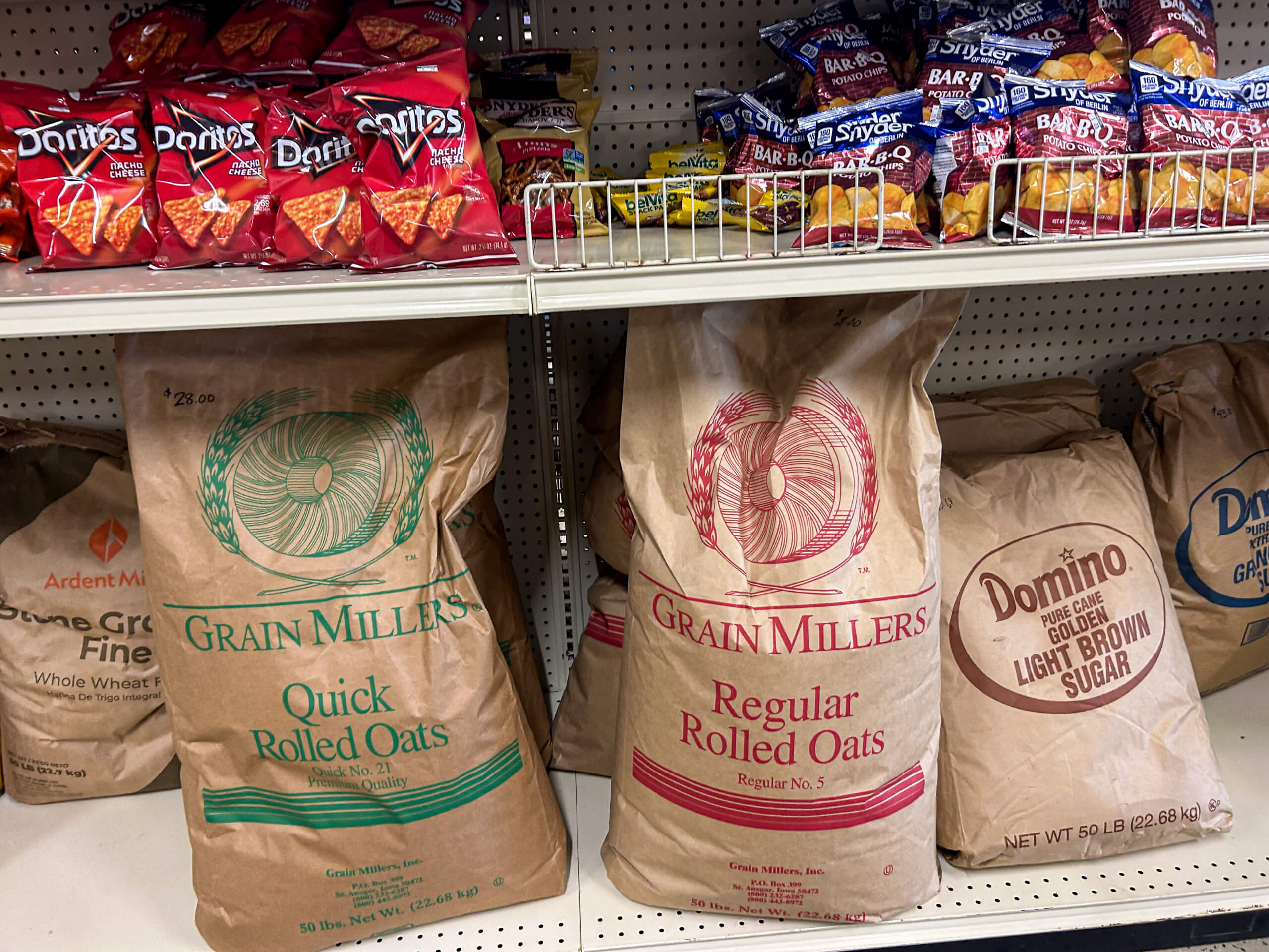 Jamar Groceries Kutztown PA Large brown paper bags of Grain Millers rolled oats and Domino light brown sugar on a store shelf, with bags of chips and pretzels on the shelf above.