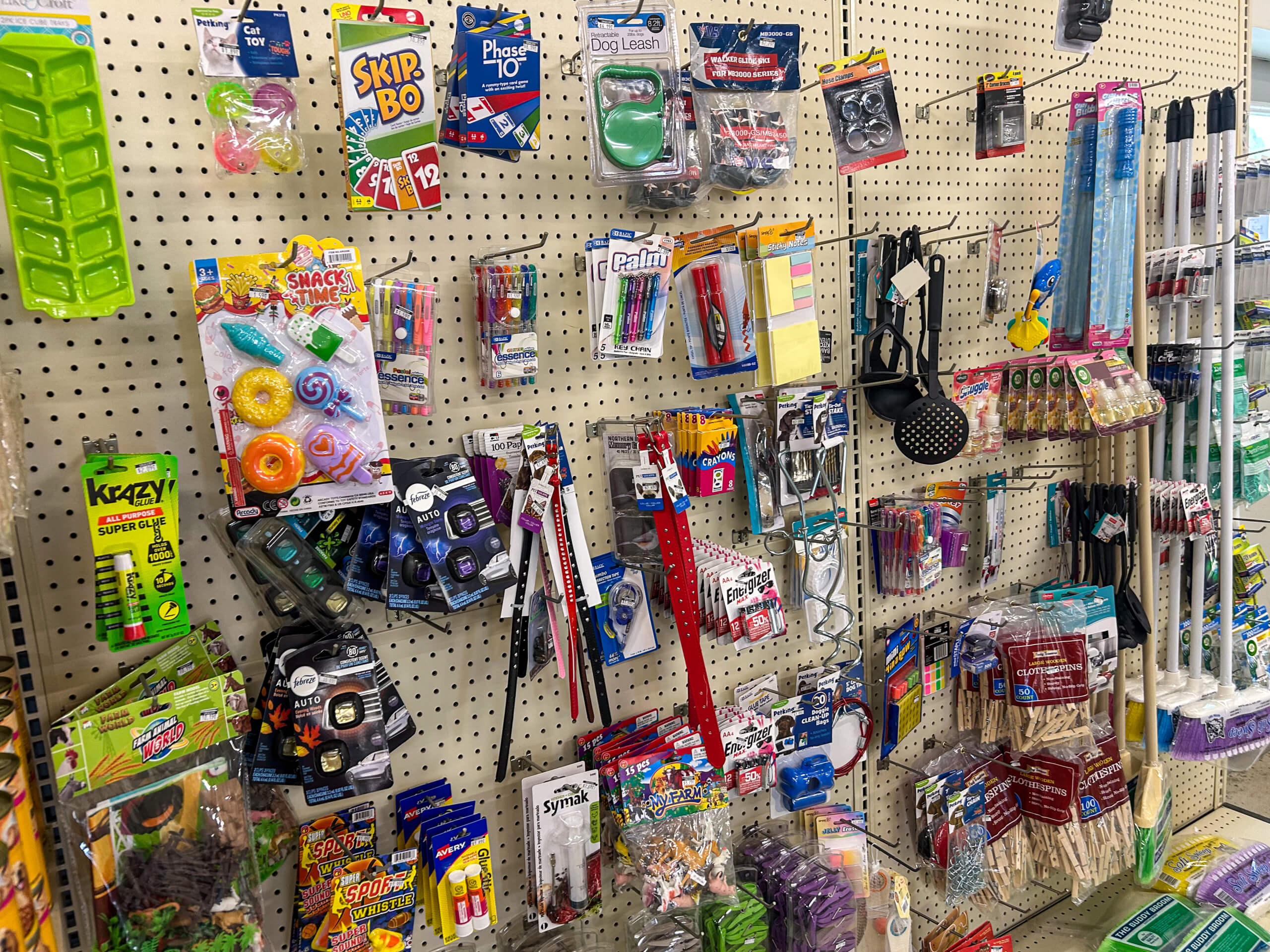 Jamar Groceries Kutztown PA A store display with various household items, pet supplies, small toys, ice cube trays, kitchen tools, and card games hanging on a pegboard wall.