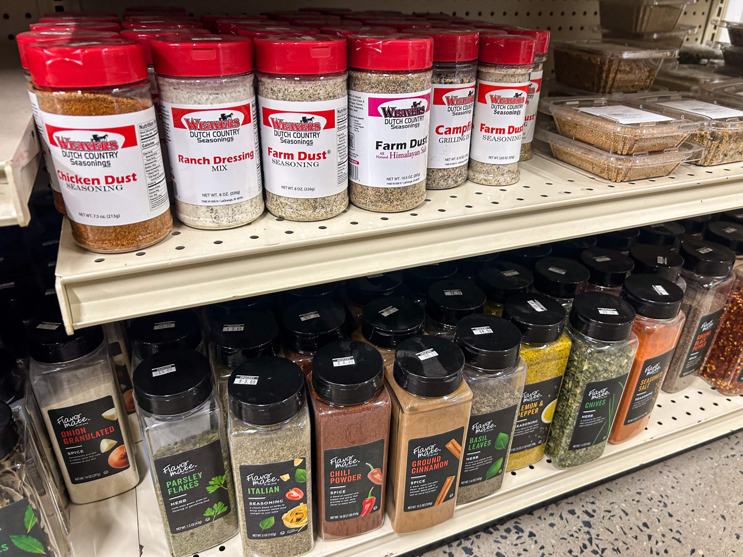 Jamar Groceries Kutztown PA Spice and seasoning containers are displayed on store shelves, including varieties like Chicken Dust, Ranch Dressing Mix, Campfire Dust, and assorted spices in clear plastic bottles.