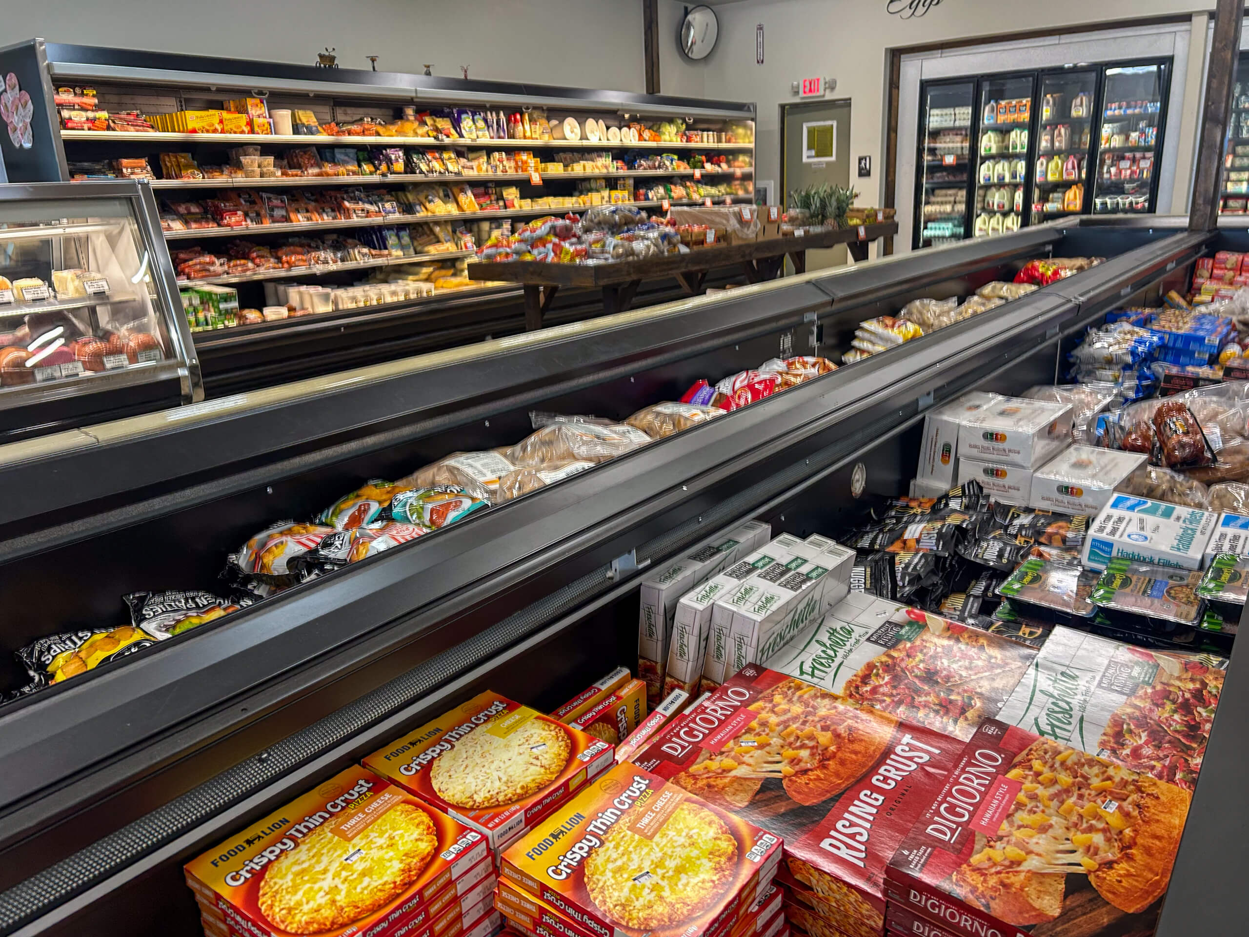Jamar Groceries Kutztown PA Grocery store aisle with frozen pizzas, vegetables, and bread in freezers and shelves stocked with various packaged foods and produce.