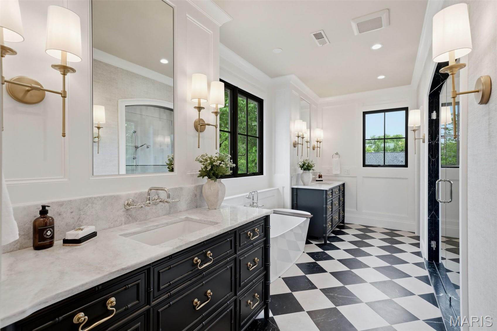 Kenrose Kitchens Custom Cabinetry Arthur IL Modern bathroom with black and white checkered floor, dual dark vanities with marble countertops, wall sconces, freestanding tub, and large windows.