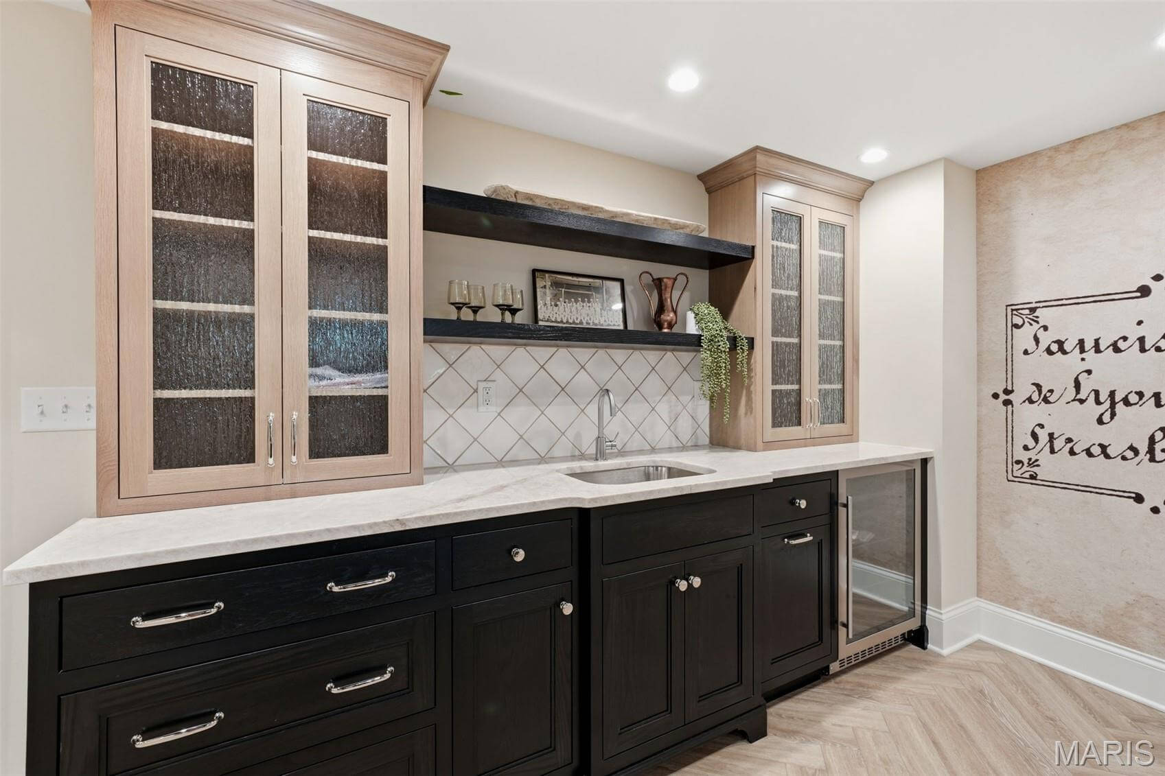 Kenrose Kitchens Custom Cabinetry Arthur IL A modern wet bar with glass-front upper cabinets, black lower cabinets, a sink, open shelving, and a small built-in refrigerator.