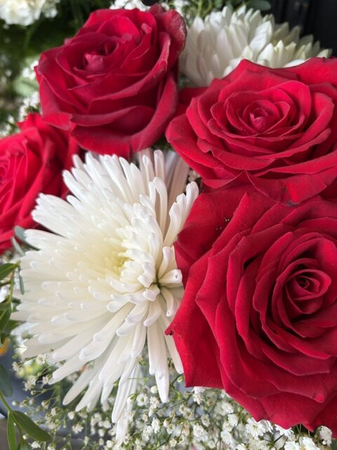 Swampy Hollow Greenhouse Gallery Cochranville, PA Close-up of a bouquet featuring red roses, white chrysanthemums, and small white filler flowers.