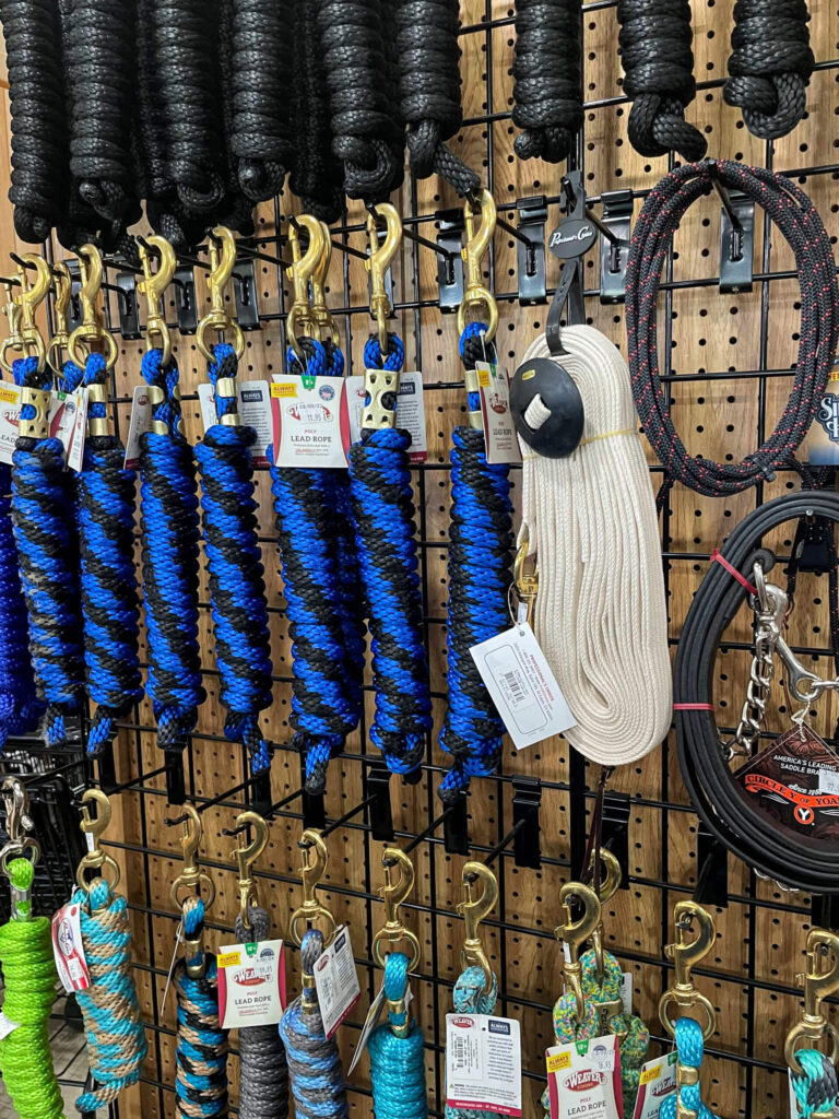 Penchem Tack Store Guthrie, KY Assorted ropes, leads, and cables with metal clips hanging on a pegboard display in a store.