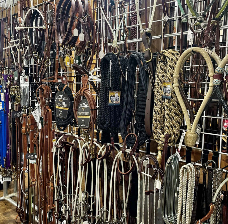 Penchem Tack Store Guthrie, KY Various horse tack items, including reins, bridles, and ropes, are displayed on metal racks in a store.